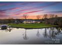 Stunning aerial view of waterfront home with lush lawn and lake access at twilight at 49461 River Run Rd, Albemarle, NC 28001