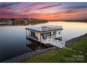 Waterfront boat dock with sunset views, featuring covered seating and a rooftop deck at 49461 River Run Rd, Albemarle, NC 28001