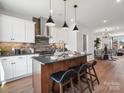 Kitchen island with seating and a sink featuring stainless steel appliances and modern pendant lighting at 5731 Castlerea Dr, Charlotte, NC 28217