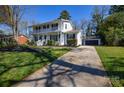 View of the white brick home with a double front porch and driveway leading to a two-car garage at 5943 Charing Pl, Charlotte, NC 28211