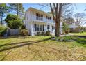 White brick home with a double front porch surrounded by a well-maintained lawn and mature trees at 5943 Charing Pl, Charlotte, NC 28211