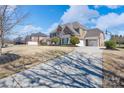 Long driveway leading to a stately brick home with a three-car garage and lush, landscaped front yard at 10005 Chimney Dr, Waxhaw, NC 28173