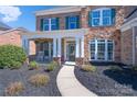 Charming home exterior with stone accents, a cozy porch, and verdant landscaping leading to the front door at 10005 Chimney Dr, Waxhaw, NC 28173