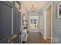 Entryway featuring stylish wallpaper, light fixture, console table, and view into the sunny living room at 138 Scofield Rd, Charlotte, NC 28209