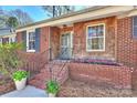 Inviting brick porch with vibrant flowers, wood details, and updated windows at 138 Scofield Rd, Charlotte, NC 28209
