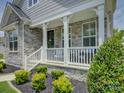 Inviting front porch with stone accents, white railings, and decorative landscaping at 14230 Morningate St, Huntersville, NC 28078