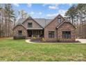 Beautiful single-Gathering home with stone and brick exterior, complemented by a lush green lawn and mature trees at 1770 Cranwell Dr, Mt Ulla, NC 28125