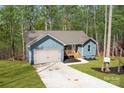 Eye-level view of the pleasant blue home, boasting a two-car garage and welcoming wood porch at 186 Byers Rd, Troutman, NC 28166