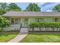 Charming home with lush landscaping, a cozy bench, and a inviting front door with wreath at 2144 Shadyview Dr, Charlotte, NC 28210