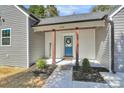 Inviting front entrance with charming blue door, 'welcome' sign, and manicured landscaping at 244 N Race St, Statesville, NC 28677
