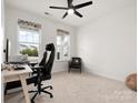 Cozy office with two large windows, neutral carpet, a ceiling fan, and comfortable office furniture at 3008 Quinebaug Rd, Fort Mill, SC 29715
