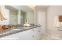 Bright bathroom featuring granite countertop with double sinks, white cabinetry, and tiled floors at 113 Asmodean Ln, Troutman, NC 28166
