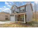 This two-story home has gray siding, a covered porch with stone accents, and an attached single-car garage at 3944 Wade E Morgan Rd, Charlotte, NC 28269