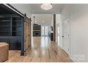 Bright open-concept living room with hardwood floors, a fireplace, and a barn door at 7403 Grassy Ridge Rd, Denver, NC 28037