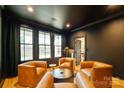 Cozy sitting room with black walls, hardwood floors, and four orange armchairs at 7403 Grassy Ridge Rd, Denver, NC 28037