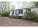 Inviting single-story home with a brick foundation and cozy front porch seating, surrounded by lush greenery at 7597 Webbs Rd, Denver, NC 28037
