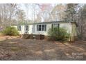 Single-story home with a brick foundation and porch, nestled among trees at 7597 Webbs Rd, Denver, NC 28037