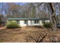 Single-story house with brick foundation, green roof, and shrubs, offering classic charm and curb appeal at 7597 Webbs Rd, Denver, NC 28037