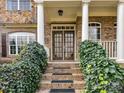 Beautiful brick home entrance featuring a double door, brick steps, and lush landscaping at 1110 Woodhall Dr, Huntersville, NC 28078