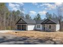 A single-story home with gray shingle and stone accents, set against a backdrop of trees and sky at 24 Eastwinds Dr, Hickory, NC 28601