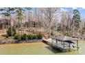 Scenic view of boat dock on the lake and wooded surroundings, with lake house in the background at 4633 River Bluff Ct, Charlotte, NC 28214