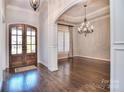 Elegant foyer with dark hardwood floors, grand chandelier, and beautiful archway to living spaces at 13008 Ginovanni Way, Mint Hill, NC 28227