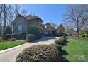 Charming stone and brick home with mature landscaping along driveway for enhanced privacy and curb appeal at 13008 Ginovanni Way, Mint Hill, NC 28227