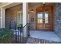 Inviting front porch featuring double doors, brick columns, and a cozy seating area at 13008 Ginovanni Way, Mint Hill, NC 28227