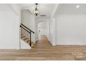Bright foyer with hardwood floors, staircase with wrought iron railing, and elegant lighting fixture at 160 Belfry Loop, Mooresville, NC 28117