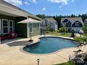 Inviting backyard pool area with a colorful umbrella, lounge seating, and well-maintained landscaping at 1638 Sweetmoss Loop, Denver, NC 28037