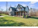 Beautiful home boasts a covered porch with timber columns and a lush green lawn at 180 Twin Sisters Ln, Mooresville, NC 28117