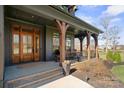 Inviting front porch with timber columns, seating area, and a beautiful solid wood front door at 180 Twin Sisters Ln, Mooresville, NC 28117