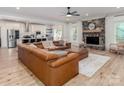 Open-concept living room flows into modern kitchen, complete with stone fireplace, hardwood floors, and large sofa at 207 Windsor Greene Dr, Monroe, NC 28110