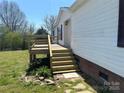 Side view of home featuring a wooden deck with stairs, brick foundation, and vinyl siding at 24257 Austin Rd, Albemarle, NC 28001
