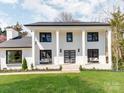 Stunning white brick two-story home with large pillars, black trim, covered entry, and expansive front lawn at 7801 Snowden Ln, Charlotte, NC 28270