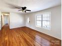 Spacious living room featuring gleaming hardwood floors, ceiling fan, and a large window at 898 Sage Field Ln, Lincolnton, NC 28092