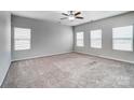 Spacious carpeted living room flooded with natural light from multiple windows and a ceiling fan at 11203 Chapeclane Rd, Charlotte, NC 28278