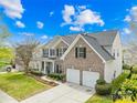 Two-story brick home with a two-car garage, manicured lawn, and mature landscaping at 13514 Porter Creek Rd, Charlotte, NC 28262