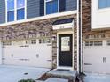 Close-up of townhome exterior with stone accents, front door, and two-car garage at 1814 Shumard Ln, Charlotte, NC 28205