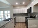 Modern kitchen featuring granite countertops, stainless steel appliances, white cabinets, and a gray subway tile backsplash at 18840 Nautical Dr # 57, Cornelius, NC 28031