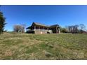 A view of the brick house featuring a covered porch on a sprawling green lawn at 3615 Wellman Rd, Vale, NC 28168