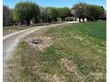 Gravel driveway leading to a brick house on a vast rural landscape featuring grassy areas and mature trees at 3615 Wellman Rd, Vale, NC 28168