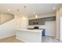 Open kitchen boasts a spacious island, stainless steel microwave, gray cabinets, and modern pendant lights at 8021 Lerwick Trl, Charlotte, NC 28269