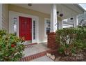 Inviting front entrance with a vibrant red door, decorative sidelights, and manicured greenery at 1100 Millbank Dr, Matthews, NC 28104