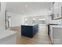 Open-concept kitchen with a navy island, white cabinets, stainless steel appliances, and hardwood floors at 2016 Bramble Hedge Rd # 3277, Indian Trail, NC 28079