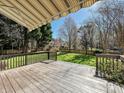 Outdoor wooden deck with railing overlooking a green backyard with mature trees and a partial awning at 20313 Queensdale Dr, Cornelius, NC 28031