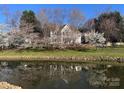 Inviting home overlooking the water, surrounded by mature trees and blossoming flowers, offering a serene and picturesque setting at 20313 Queensdale Dr, Cornelius, NC 28031