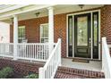 Inviting front porch with classic brickwork, white columns and railing, and decorative glass door at 615 Vega Nw St, Concord, NC 28027