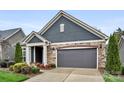 Home exterior featuring stone accents, a two-car garage, manicured lawn, and a welcoming covered front entrance at 7909 Parknoll Dr, Huntersville, NC 28078