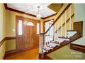 Grand foyer featuring hardwood floors, detailed trim, a stained-glass door, and staircase with white spindles at 9951 Providence Forest Ln, Charlotte, NC 28270